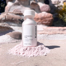 Load image into Gallery viewer, Seen here: Kavana's Purfying powder face mask, standing tall in a pile of the powder. A relief of rose coloured rocks in the background and sunlight streaming down on the bottle.