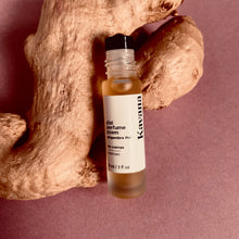 Load image into Gallery viewer, PMS cramps got you down? Find support with this Plai (Thai Ginger) roll on. Try Kavana's powerful Perfume Poem blend, including Plai (Thai ginger) and Marjoram essential oils, to help ease the pain of monthly cramps.  Seen in this photo: a roller ball on rosted glass bottle 10ml, with a matte silver cap, resting on a large piece of fresh ginger.
