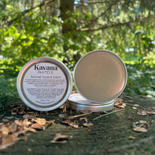 Load image into Gallery viewer, Kavana Phyto-5 Boreal Beard Balm pictured here on a tree stump, opened, with some pine cones around it. Pale green, thanks to the kaolin and French Green clays in it, this balm is smooth and tacky at the same time. This lightweight pomade can be used to style and groom the beard hair.