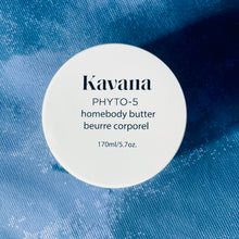 Load image into Gallery viewer, Kavana Phyto-5 Homebody Butter seen here from the top, on a blue background. Just the round cap, white label with black writing. Great for deeply hydrating very dry, parched, cracked skin. Also great for expecting mother's, as a rich belly butter. A perfect gift for anyone!