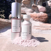 Load image into Gallery viewer, Seen here: Kavana's Purifying Cream Cleanser (30ml/1fl.oz) bottle, standing up side by side with Kavana's Purifying Face Mask, in a pile of the mask or powder. Both bottles are closed and upright, the background is rosy coloured stones and some sky peaking through forest.