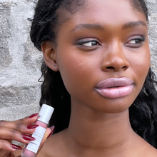 Load image into Gallery viewer, Model Raissa is seen wearing Kavana&#39;s Phyto-5 TInted lip oil in shade Sublime, which she is also holding up near her face.
