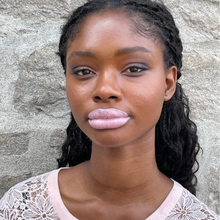 Load image into Gallery viewer, Model Raissa is seen wearing a pale pink sweater to match Valentine- a pale golden lilac lip oil shade, one of 13 of Kavana&#39;s Phyto-5 Tinted LIp oils.
