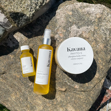 Load image into Gallery viewer, Kavana&#39;s Afterglow trio is plant powered body care at it&#39;s finest. Pictured, our mini travel size body oil, large body oil and large Body Cream, arranged side by side lying on a flat rock. 
