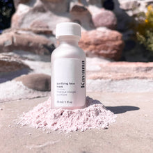 Load image into Gallery viewer, Seen here: Kavana&#39;s Purfying powder face mask, standing tall in a pile of the powder. A relief of rose coloured rocks in the background and sunlight streaming down on the bottle.
