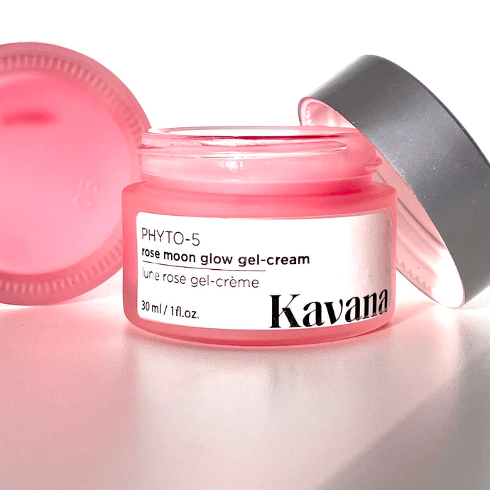 Rose Moon Glow Gel Cream is a lightweight primer and moisturizer, 2-in-1. Pictured here, the open jar with a brushed, matte silver coloured cap, perched on the lip of the jar. Another jar flipped on it's side, cane be seen, the pink colour of the gel showing through it. This gel goes on clear on the skin, leaving now colour behind. 