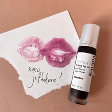 Load image into Gallery viewer, Kavana&#39;s PHyto-5 TInted Lip Treatment oil seen here, is closed- silver cap on a frosted glass roll ball bottle, sits on top of a note with a lip print and the words &#39;je &#39;tadore&#39; written in french and an &#39;xoxo&#39; underneath the lip print. A cute Valentines Day note quoi?
