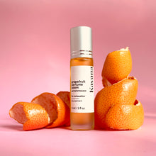 Load image into Gallery viewer, Kavana&#39;s Grapefruit Perfume Poem pictures with fruit rind curled into ribbons alongside the roll-on perfume bottle made of frosted glass with a pale, matte silver cap. This perfume has essential oils of grapefruit, lavender, eucalyptus and sweet orange to help uplift a tired gal. Find it at kavanaskincare.com
