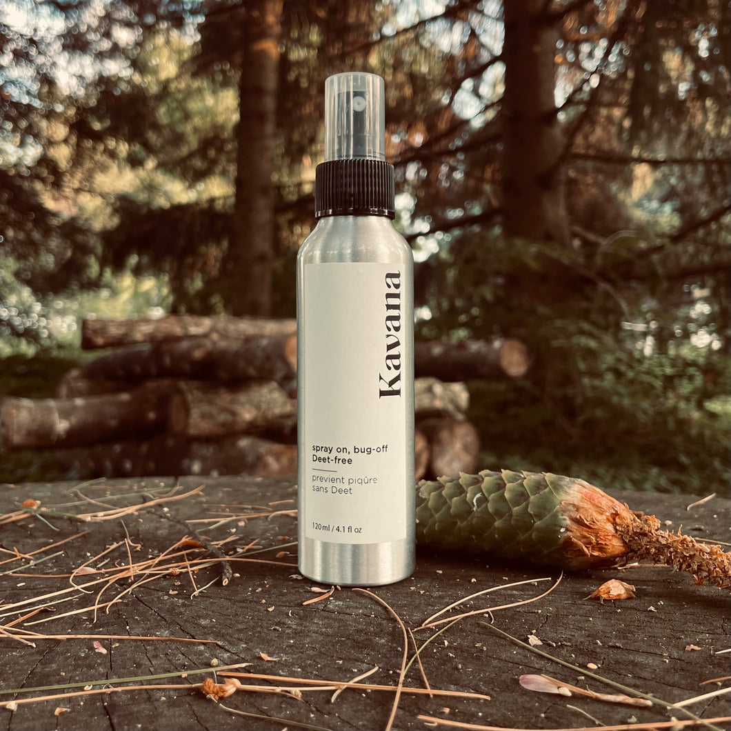 Kavana beloved and bestselling DEET free bug spray, now in an aluminum mister, lightweight and great for camping trips. Pictured here on top of a tree stump with a bright green pine cone nd logs behind it. 4fl. oz. 