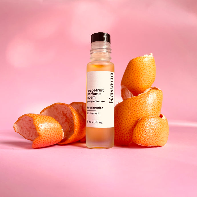 Kavana's Grapefruit Perfume Poem is a non-toxic, clean, oil-based roll on perfume. Pictured here with grapefruit rind curled into ribbons alongside the roll-on perfume bottle. Made of frosted glass with a pale, matte silver cap. This perfume has essential oils of grapefruit, lavender, eucalyptus and sweet orange to help uplift a tired gal suffering from exhaustion and insomnia during her cycle, perimenopause, menopause and during pregnancy and post partum. Find it at kavanaskincare.com