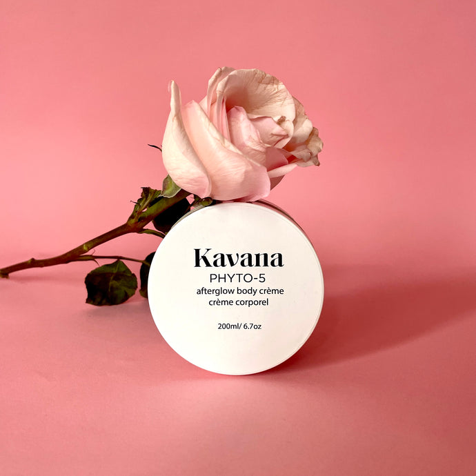 Kavana's Phyto-5 Afterglow Body Cream is light but luscious and perfectly layers under Kavana's lighweight Afterglow Body oil. Seal moisture in skin all season with these two. Seen here, the cream lies flat on a rock, opened, the cover lies flat on the upper right hand side of it. The cream is a pale ivory yellow tone. Perfect or those who intentionally seek to embody intention, using non-toxic, hormone safe, plant powered skincare.