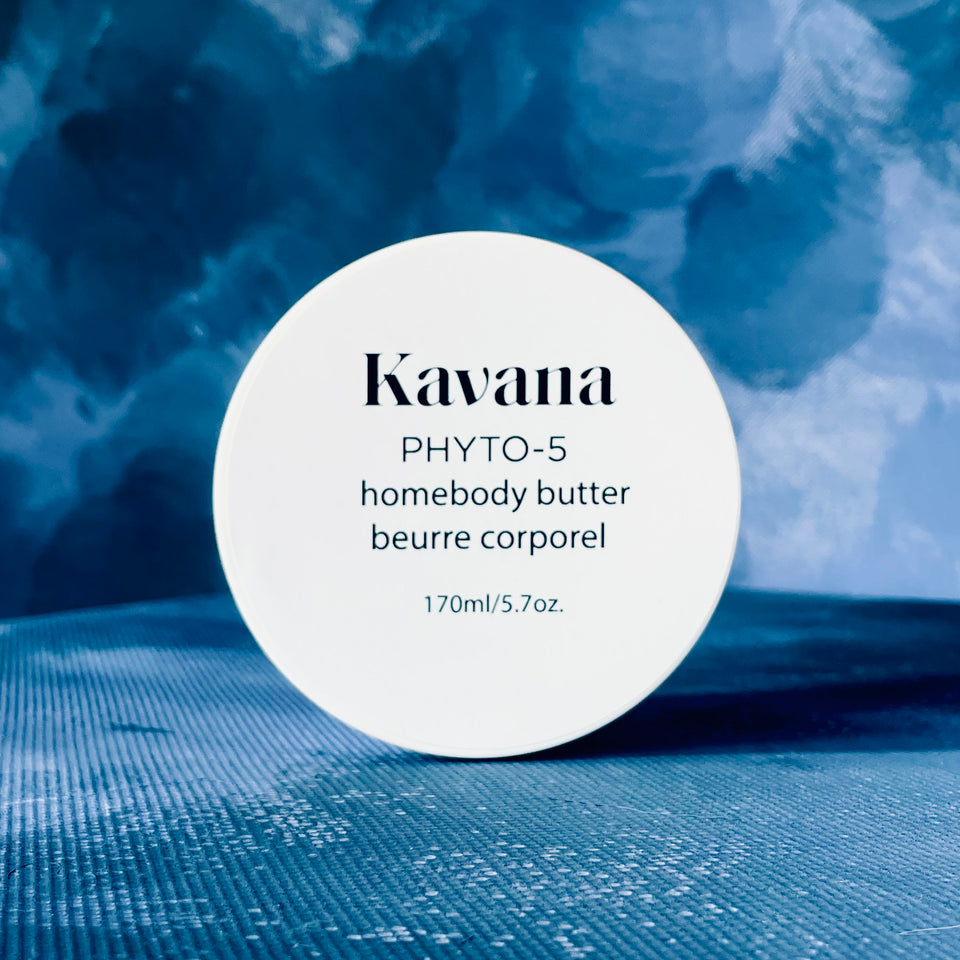 Kavana Phyto-5 Homebody Butter seen here from the top, on a blue background. Just the round cap, white label with black writing. Great for deeply hydrating very dry, parched, cracked skin. Also great for expecting mother's, as a rich belly butter. A perfect gift for anyone!