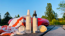 Load image into Gallery viewer, Kavana Summer quad, consists of the pictured products, from left to right: Skin Saver Salve, Skin Saver Mist, Bug OFF Mist, Eco-Deodorant bar. Pictured standing in front of a towel, draped over an orange, life saving buoy.
