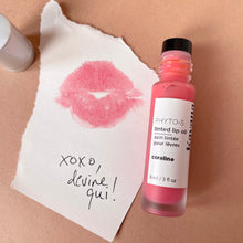 Load image into Gallery viewer, Kavana&#39;s Phyto-5 Tinted Lip Treatment Oil is a  sheer, pale pinky coral, tone. The bottle is open here and the lip print on the note is signed &#39;xoxo, devine qui&#39;, french for &#39;guess who;. 
