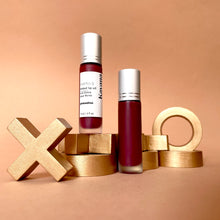 Load image into Gallery viewer, Kavana&#39;s PHyto-5 tinted lip treatment oil in shade Grenadine, is a sheer pomegranate red, berry tint for lips. Seen open over top of a love note, the roll on bottle looks like it was just used. The note says u &amp; i on it with a lip print in the colour. 
