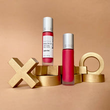 Load image into Gallery viewer, Kavana&#39;s Phyto-5 Tinted Lip Treatment oil in shade Capucine, a bright, summery coral, is seen closed here, overtop of a love note that says &#39;xoxo, ta puce&#39;. French for hugs and kisses, your love bug.
