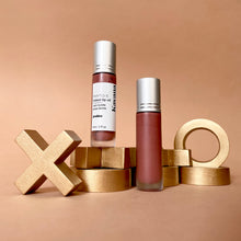 Load image into Gallery viewer, Kavana&#39;s Phyto-5 Tinted Lip Treatment Oil in Praline, a soft shade of rosy brown, THE perfect neutral for everyday wear. Seen here, the open roll on bottle with cap off, sits atop a love note that is signed &#39;xoxo, ta douce moitie&#39;, kisses from your better half. 
