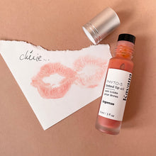 Load image into Gallery viewer, Kavana&#39;s phyto-5 Tinted Lip Treatment oil in shade Ingenue, is a sheer, perfect peach for everyday or with a smokey eye! The bottle is opened and sits atop a note that says &#39;cherie&#39; on it with a lip print in pale peach.
