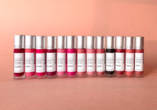 Load image into Gallery viewer, All of Kavana&#39;s Phyto-5 Tinted lip Treatment oils lined up side by side, touching, the colours on display include a range of 13 different tints from pink to red, to browns and dark plums, a nice variety for every skin tone!

