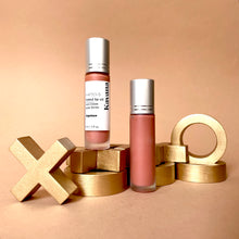 Load image into Gallery viewer, Kavana&#39;s phyto-5 Tinted Lip Treatment oil in shade Ingenue, is a sheer, perfect peach for everyday or with a smokey eye! The bottle is opened and sits atop a note that says &#39;cherie&#39; on it with a lip print in pale peach.
